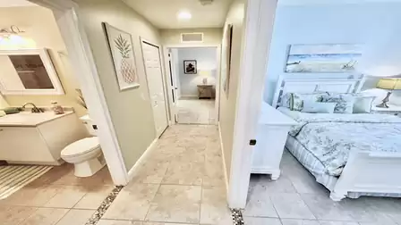 Hallway with tiled floors, modern bathroom on the left and bedroom with a double bed on the right; bright layout with direct access to all rooms.