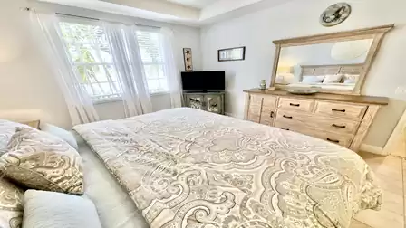 Bedroom with king-size bed, dresser, and TV, bright and comfortably furnished.