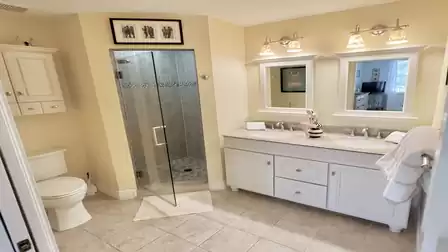 Modern bathroom with walk-in shower, double vanity, ample storage, and direct access to the bedroom.
