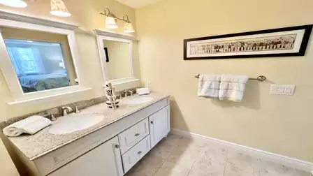 Bathroom with double vanity, granite countertop, dual mirrors, and bright lighting