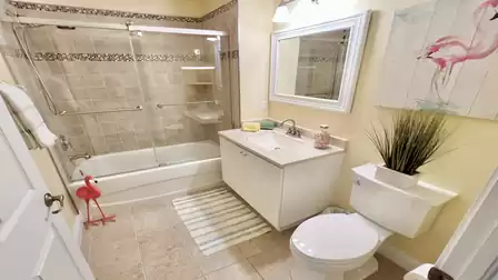 Bathroom with bathtub, glass shower screen, vanity, mirror, and toilet