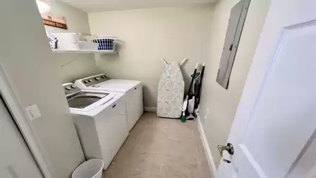 Laundry room with washer, dryer, ironing board, and storage space for laundry