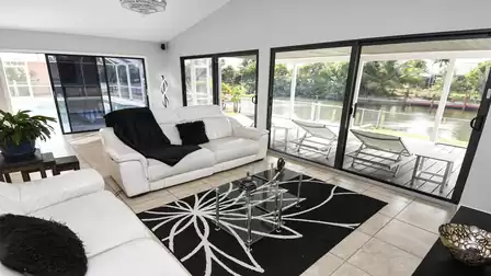 Bright living area with sofas, large windows and views of the terrace and canal