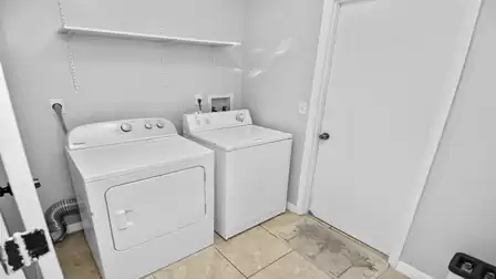 Laundry room with washer, dryer, wall shelf, and tiled floor