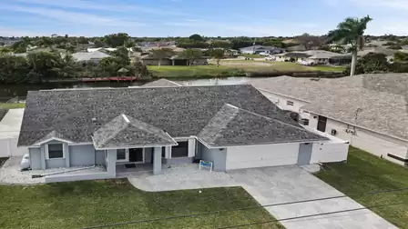 Aerial view of the villa with garage, driveway and canal in a residential area