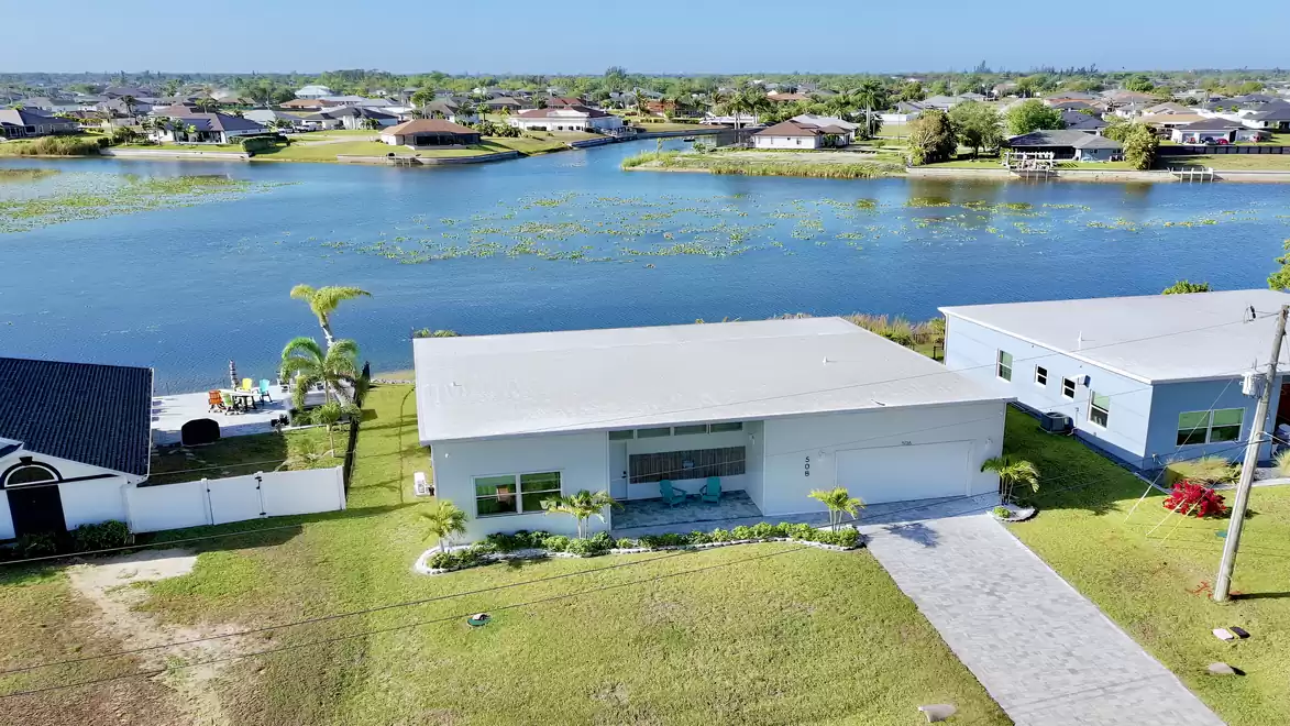 Aerial view of a modern waterfront vacation home with a spacious property and stunning lake views.