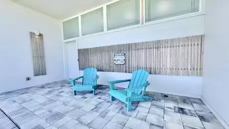 Covered entrance patio with comfortable Adirondack chairs and modern design for relaxing vacation moments.