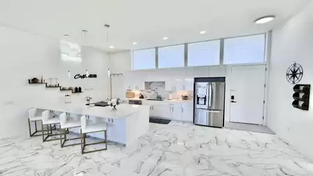Bright modern kitchen with a large island, premium appliances, and elegant marble-style finishes.