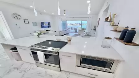 Open-plan kitchen with a large island, modern appliances, and direct views of the living area and waterfront.