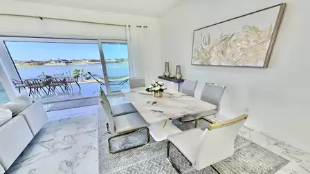 Elegant dining area with lake views, a modern dining table, and direct access to the waterfront terrace.