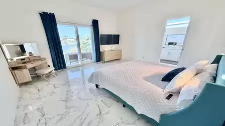 Bright bedroom with a king-size bed, smart TV, lake views, and direct access to the private bathroom.
