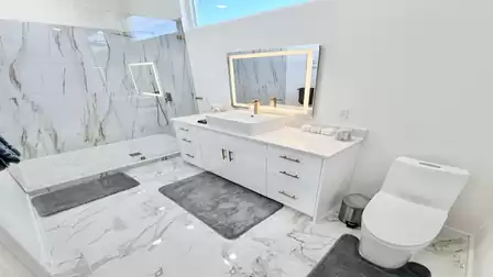 Modern bathroom with a walk-in rain shower, stylish vanity, and elegant marble-style finishes.