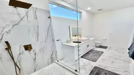 Luxurious bathroom with a walk-in rain shower, modern vanity, and elegant marble-style finishes.