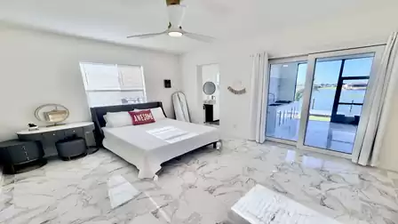 Bright bedroom with a queen-size bed, lake views, and direct access to the covered waterfront terrace.