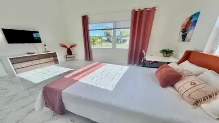 Bright bedroom with a king-size bed, smart TV, and a practical workspace in a modern, comfortable setting.
