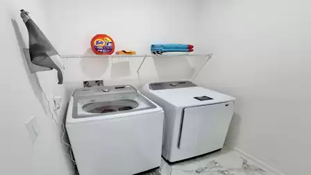 Practical laundry room with a washer, dryer, and extra storage space for a comfortable stay.