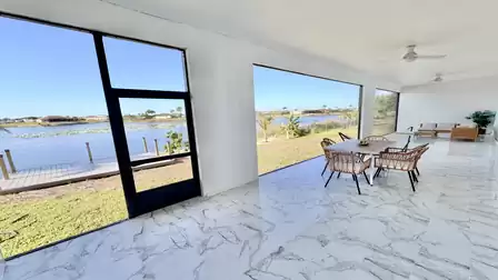Spacious covered waterfront terrace featuring a stylish dining area, comfortable lounge seating, and stunning views across the lake.