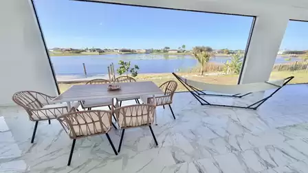 Covered lakeside terrace with a spacious dining area, hammock, and private dock - perfect for relaxing moments with stunning waterfront views.