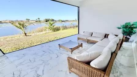 Cozy lounge area on the covered lakeside terrace with comfortable seating and unobstructed water views - ideal for relaxing outdoor vacation moments.