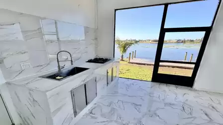 Premium outdoor kitchen on the covered lakeside terrace featuring a grill, sink, and direct access to the private dock - perfect for social evenings with stunning waterfront views.