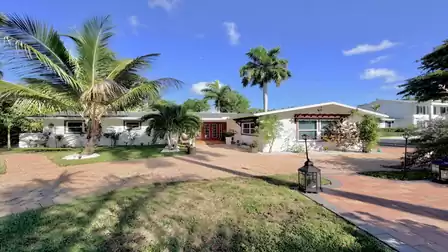 River District Retreat vacation villa in Fort Myers featuring tropical landscaping, palm trees and a spacious driveway.