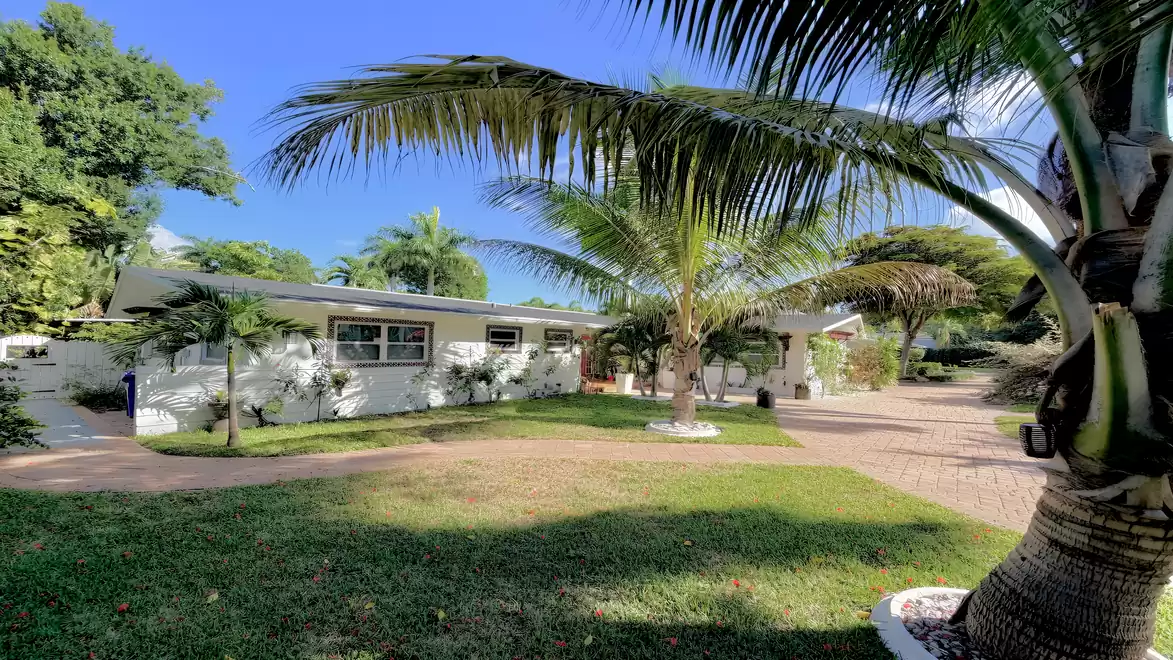 Side view of the vacation villa in Fort Myers featuring tropical landscaping, palm trees and a spacious driveway.