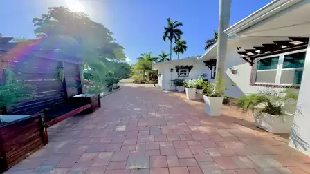 Sunny entrance area of the vacation villa in Fort Myers with tropical landscaping, palm trees and stylish seating.