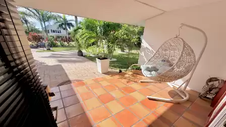 Covered entrance patio of the vacation villa in Fort Myers with a hanging chair, tropical plants and a relaxing atmosphere.
