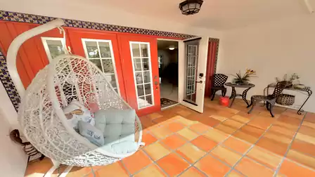 Inviting entrance patio of the vacation villa in Fort Myers with a hanging chair, Mediterranean-style tiles and cozy seating.