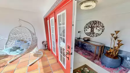 Stylish entrance area of the vacation villa in Fort Myers featuring a hanging chair, red French doors and an inviting foyer.