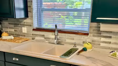 Close-up of the modern kitchen featuring a spacious double sink, stone-look countertop and garden views.