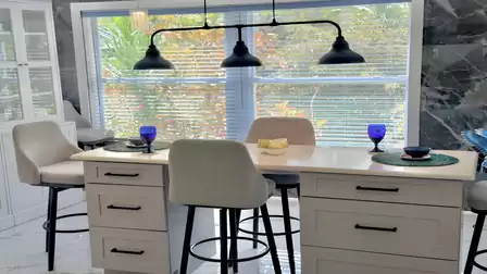 Elegant dining area featuring a spacious kitchen island, comfortable bar stools, and a large picture window overlooking tropical greenery - perfect for shared meals and relaxed vacation moments.