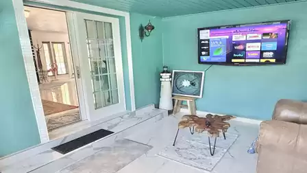 Separate TV lounge with a smart TV, comfortable recliner, and coastal-inspired décor - perfect for relaxing movie nights and peaceful vacation moments.