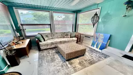 Bright sunroom with expansive windows, tropical-inspired décor, and a cozy seating area - a welcoming retreat for relaxing, reading, or enjoying views of the garden.