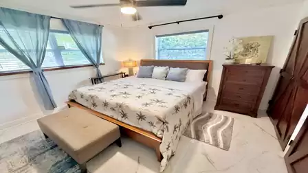 Cozy bedroom featuring a spacious double bed, warm wooden furnishings, and abundant natural light. The calming design and tropical-inspired décor create a relaxing atmosphere for a restful vacation stay.