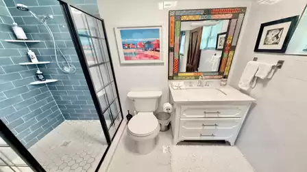 Modern bathroom with glass shower, blue tiled walls, and stylish vanity unit