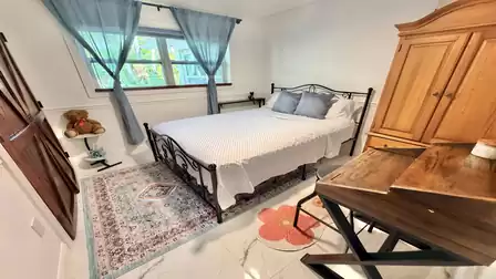 Cozy bedroom with double bed, writing desk, and garden view through the window