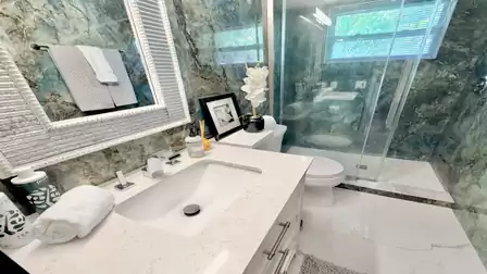 Elegant bathroom with spacious glass shower, marble-look walls, and modern vanity unit