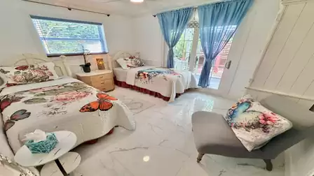 Bright bedroom with two single beds, floral décor, and access to the terrace
