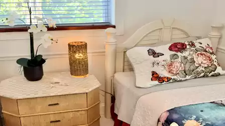 Charming sleeping area with floral accents, bedside table, and warm ambient lighting