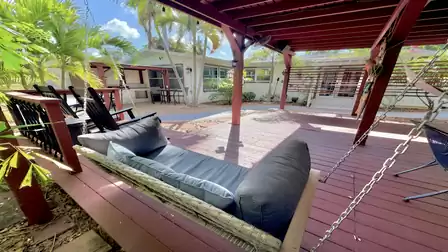 Spacious lounge deck with hanging sofa, rocking chairs, and tropical garden views