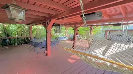 Covered outdoor lounge with hammock, seating area, and tropical garden surroundings
