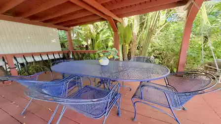 Covered terrace dining area with seating group and tropical garden surroundings