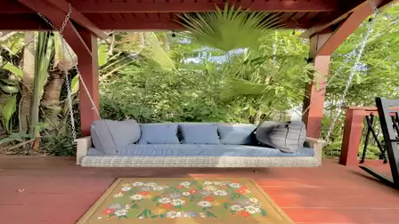 Cozy porch swing on the covered terrace surrounded by lush tropical greenery