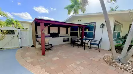Covered outdoor kitchen with grill, seating area and tropical garden setting