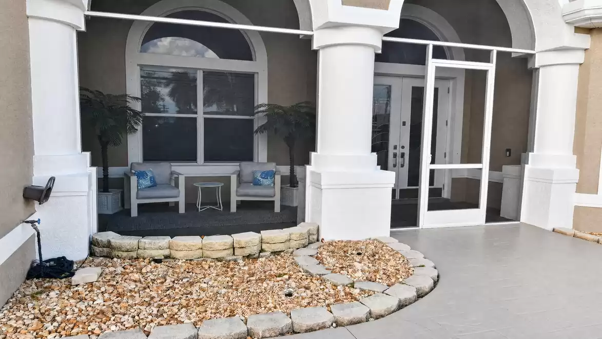 Villa Almare vacation rental Cape Coral front entrance with columns, screen door and stone landscaping