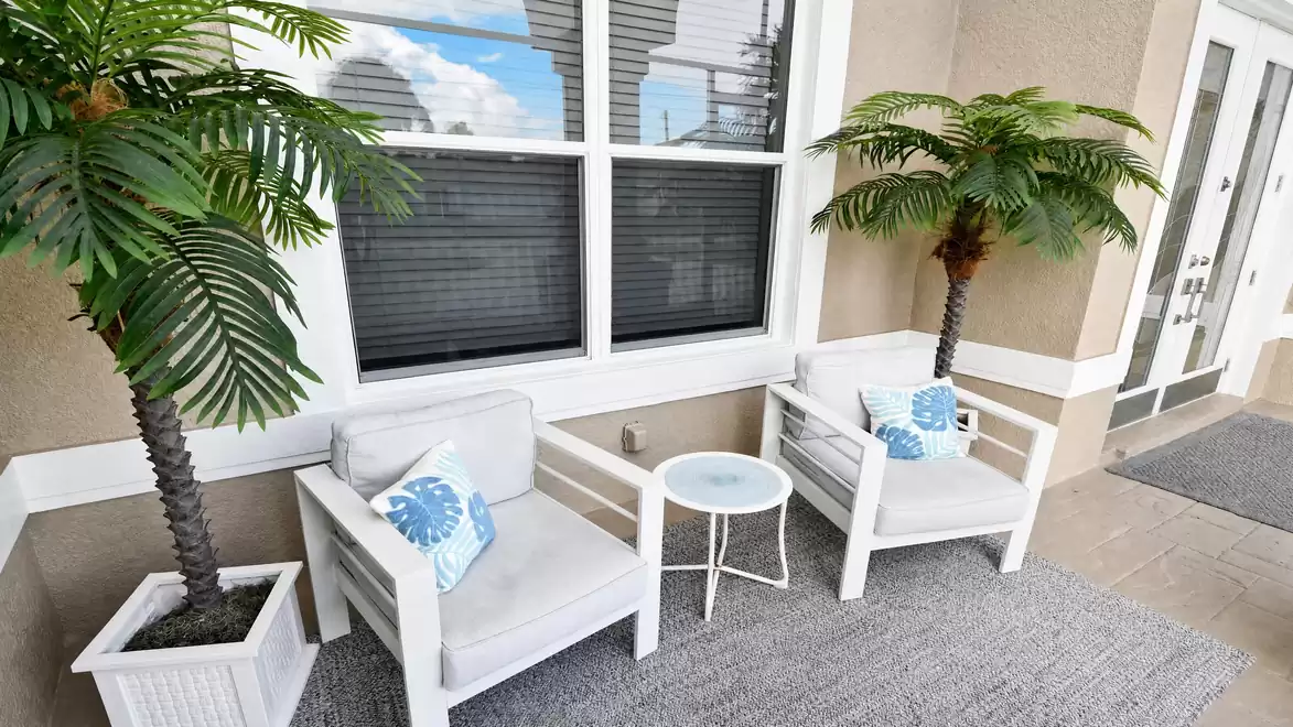 Villa Almare Cape Coral vacation home entrance nook with two armchairs, table and potted palms