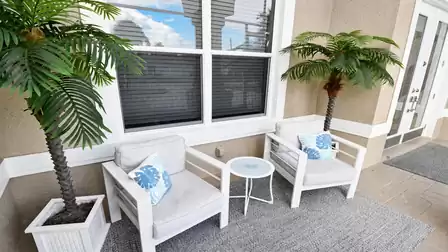 Villa Almare Cape Coral vacation home entrance nook with two armchairs, table and potted palms