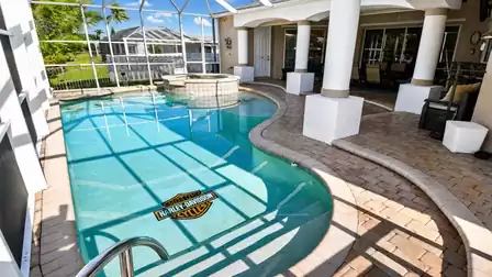 Screened pool with Harley Davidson logo, raised spa and brick pool deck with columns