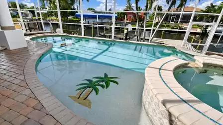 Curved swimming pool with palm mosaic, raised spa and screened canal dock behind